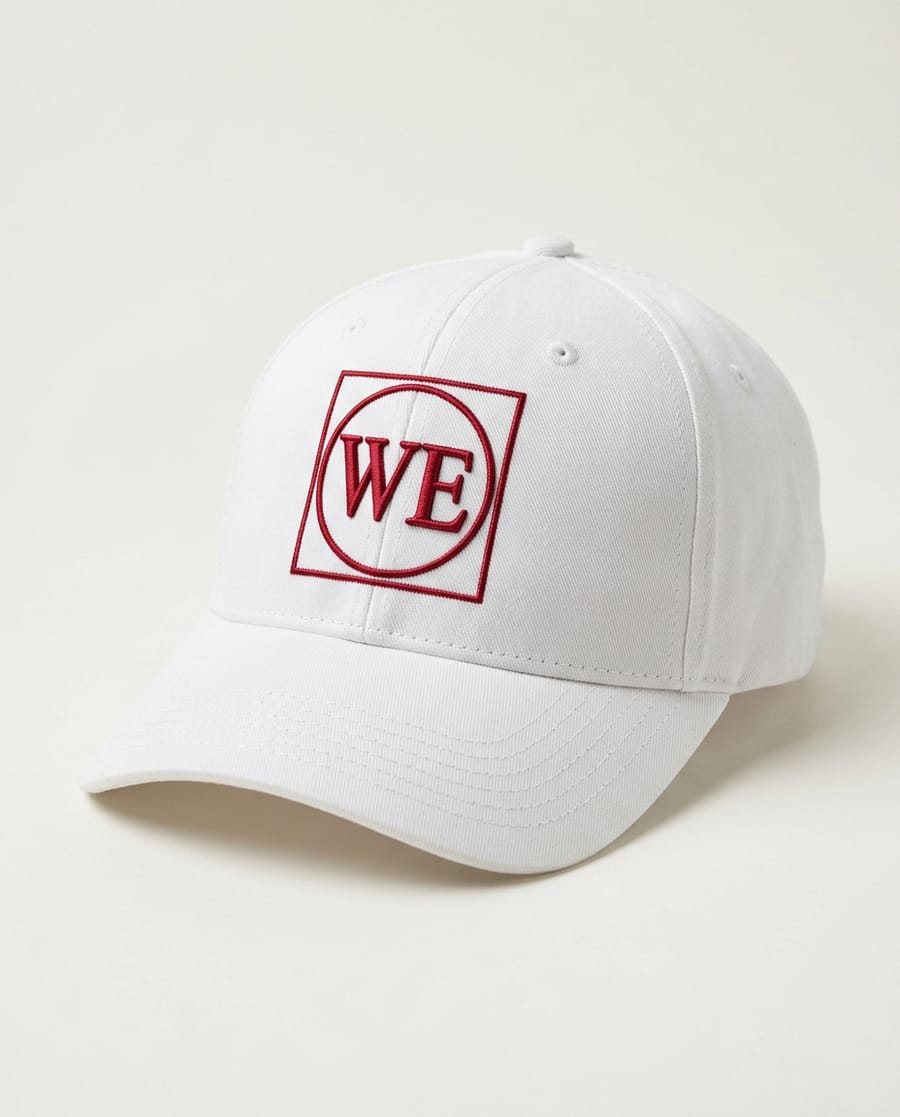 White six-panel cap with a raised red WE monogram